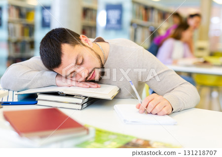 Portrait of a tired student guy lying on a desk on textbooks Portrait of a tired student guy lying on a desk on textbooks 131218707