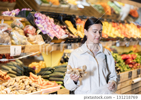 Middle-aged woman holding ginger in grocery store Middle-aged woman holding ginger in grocery store 131218769
