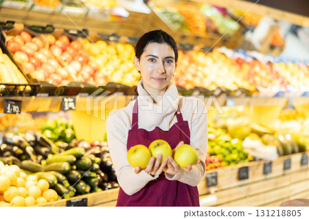 Woman staff with apple in hands working in greengrocery Woman staff with apple in hands working in greengrocery 131218805