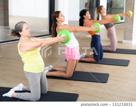 Women practicing pilates with balls at group class in yoga studio 131218831