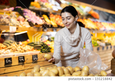 Young woman choosing potatoes in vegetable shop Young woman choosing potatoes in vegetable shop 131218842