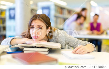 Portrait of tired woman studying at library 131218886