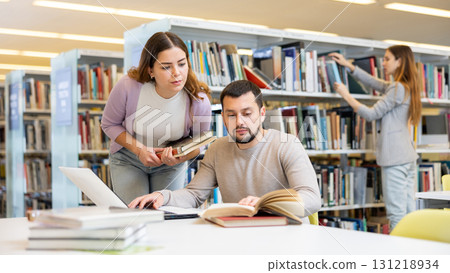 Male and female students preparing for exam together in library Male and female students preparing for exam together in library 131218934