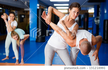 Asian woman performing elbow strike and wristlock to male opponent during self defence training Asian woman performing elbow strike and wristlock to male opponent during self defence training 131218991