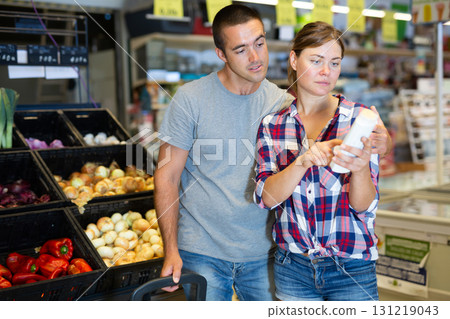 Interested couple reading product labels while shopping in supermarket 131219043