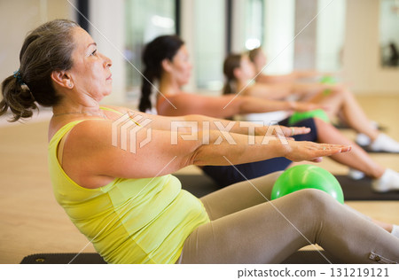 Group of women doing roll ups with bener balls Group of women doing roll ups with bener balls 131219121