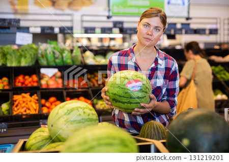 Woman choosing watermelon in supermarket 131219201