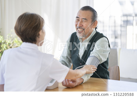 一位 70 多歲的男士面帶微笑,正在接受醫務人員的血壓測量 一位 70 多歲的男士面帶微笑,正在接受醫務人員的血壓測量 131220588