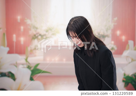一名年輕女子身穿喪服，在葬禮或守靈儀式中祈禱 131220589