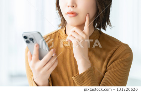 A woman thinking with a smartphone 131220620