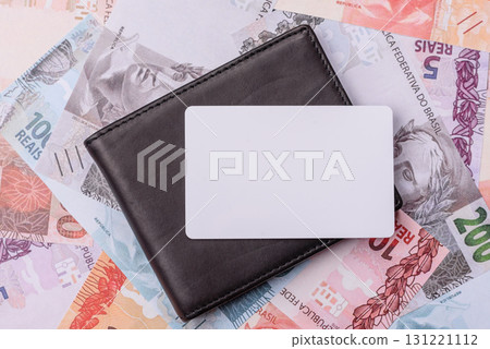 The white plastic card as a symbol of cashless payments on the background of cash paper money of Brazil 131221112