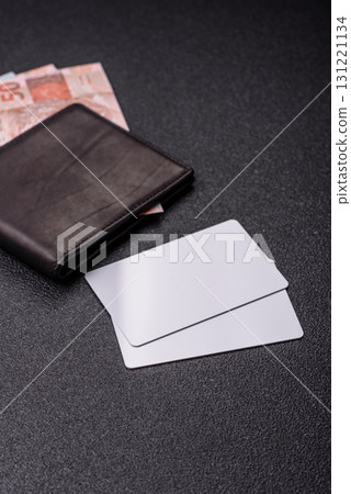 The white plastic card as a symbol of cashless payments on the background of cash paper money of Brazil 131221134