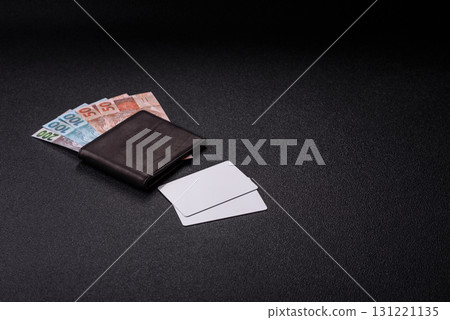 The white plastic card as a symbol of cashless payments on the background of cash paper money of Brazil 131221135