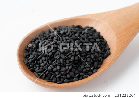 Close-up of black sesame seeds (raw sesame seeds) on a spoon on a white background Close-up of black sesame seeds (raw sesame seeds) on a spoon on a white background 131221204