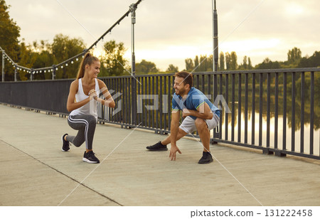 Young cheerful couple doing sport stretching exercises in nature standing on bridge. Young cheerful couple doing sport stretching exercises in nature standing on bridge. 131222458