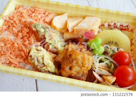A colorful and delicious homemade bento box containing salmon flake rice, fried chicken, and omelet. A colorful and delicious homemade bento box containing salmon flake rice, fried chicken, and omelet. 131222576