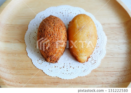 一張看起來清爽美味的烘焙食品照片，檸檬和檸檬茶口味的費南雪蛋糕擺放在木盤上 131222580
