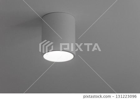 A single cylindrical ceiling light fixture casts a soft, bright glow in a modern space 131223096