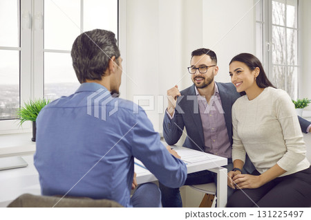 Happy young customers talking with male real estate agent or broker in office Happy young customers talking with male real estate agent or broker in office 131225497