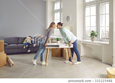 Happy family arranging furniture in a new apartment on moving day and kissing. Happy family arranging furniture in a new apartment on moving day and kissing. 131225498