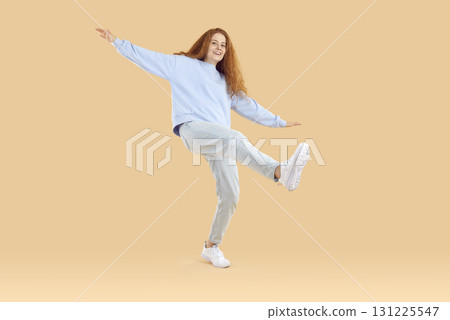 Funny teenage girl in trendy and comfortable casual outfit having fun on light beige background. Funny teenage girl in trendy and comfortable casual outfit having fun on light beige background. 131225547