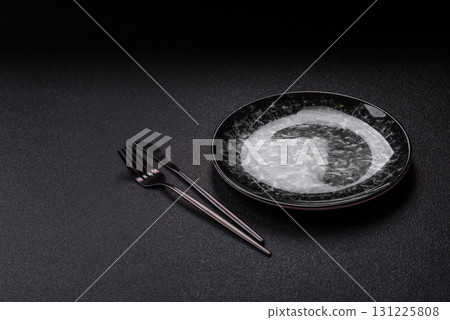Empty round black plate for food, kitchen utensils on dining table. Empty plate Empty round black plate for food, kitchen utensils on dining table. Empty plate 131225808