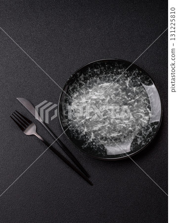 Empty round black plate for food, kitchen utensils on dining table. Empty plate Empty round black plate for food, kitchen utensils on dining table. Empty plate 131225810