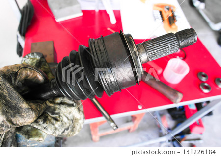 Worn CV axle joint with damaged rubber boot and visible grease leakage 131226184