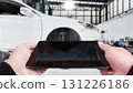 Mechanic using digital tablet with diagnostic graphs in modern auto repair shop 131226186