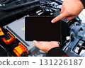 Mechanic using digital tablet with black blank screen to inspect electric vehicle battery system 131226187