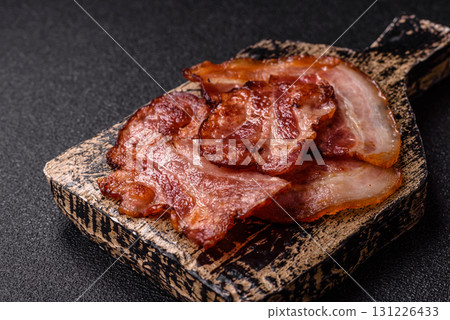 Cooked fried crispy bacon as an ingredient of a delicious English breakfast. Pieces of fried bacon Cooked fried crispy bacon as an ingredient of a delicious English breakfast. Pieces of fried bacon 131226433