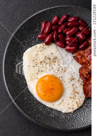 Fried egg, bacon and beans, a classic British breakfast with tomatoes. Egg, bacon and beans Fried egg, bacon and beans, a classic British breakfast with tomatoes. Egg, bacon and beans 131226589