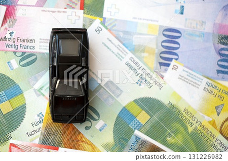 Swiss franc banknotes and toy car. The current francs money bills and black car lies on table Swiss franc banknotes and toy car. The current francs money bills and black car lies on table 131226982