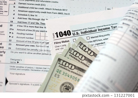Hundred dollar bills and 1040 individual income tax return form blank close up Hundred dollar bills and 1040 individual income tax return form blank close up 131227001