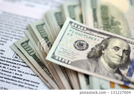 Big amount of United States dollar bills on table with tax return form close up Big amount of United States dollar bills on table with tax return form close up 131227004