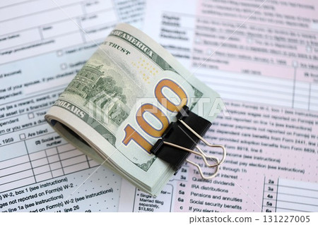 Big amount of United States dollar bills on table with 1040 tax return form 131227005