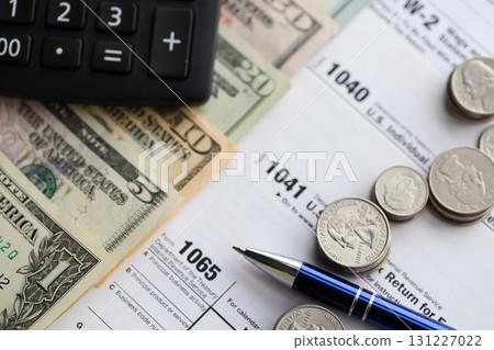 American US dollars money bills and coins with pen and calculator on IRS tax form blanks American US dollars money bills and coins with pen and calculator on IRS tax form blanks 131227022