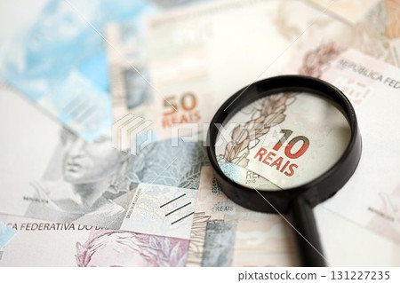 Brazilian reais banknotes and magnifying glass. The current Brazil real money bills and loupe 131227235