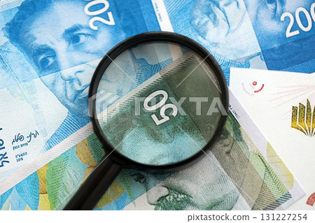 Israel New Shekels banknotes and magnifying glass. The current Israel money bills with loupe 131227254