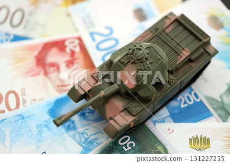 Israel New Shekels banknotes and toy tank. The current Israel money bills and tank lies on table 131227255