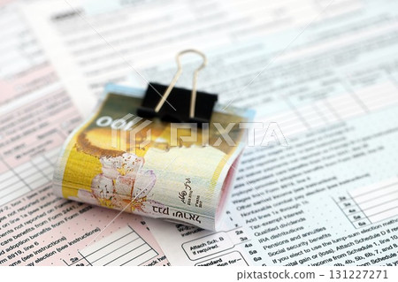 Israel New Shekels banknotes on tax form blank. The current Israel money bills lies on tax report 131227271