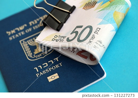 Israel New Shekels banknotes and passport on blue background. The current Israel money bills Israel New Shekels banknotes and passport on blue background. The current Israel money bills 131227273