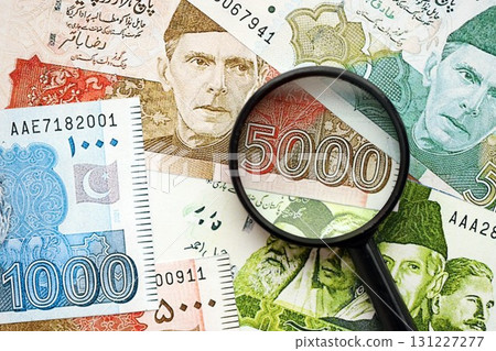Pakistan rupees banknotes and magnifying glass. The current Pakistan money bills with loupe Pakistan rupees banknotes and magnifying glass. The current Pakistan money bills with loupe 131227277