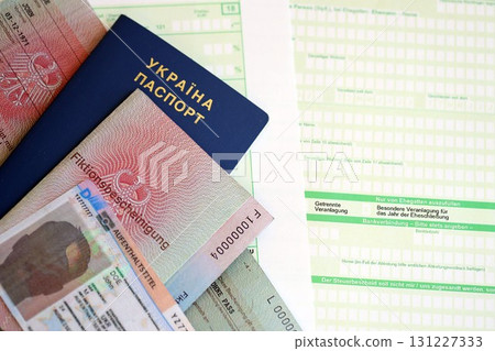 German Permanent resident card and document specimen lies with Ukrainian passport on tax form 131227333