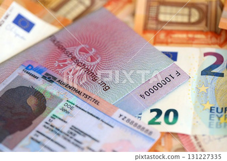 German Permanent resident card and document specimen with euro money bills lies on wooden table German Permanent resident card and document specimen with euro money bills lies on wooden table 131227335
