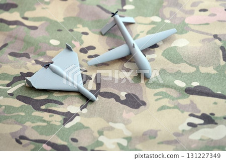 Unnamed grey toy drones models on camouflage fabric. Kamikaze drone and observation drone Unnamed grey toy drones models on camouflage fabric. Kamikaze drone and observation drone 131227349