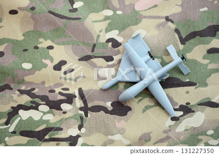 Unnamed grey toy drones models on camouflage fabric. Kamikaze drone and observation drone Unnamed grey toy drones models on camouflage fabric. Kamikaze drone and observation drone 131227350