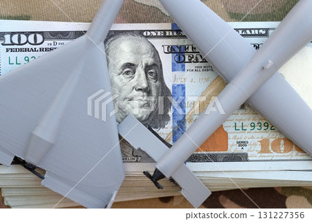 Unnamed grey toy drones on dollar bills on camouflage fabric. Drone manufacturing funds Unnamed grey toy drones on dollar bills on camouflage fabric. Drone manufacturing funds 131227356