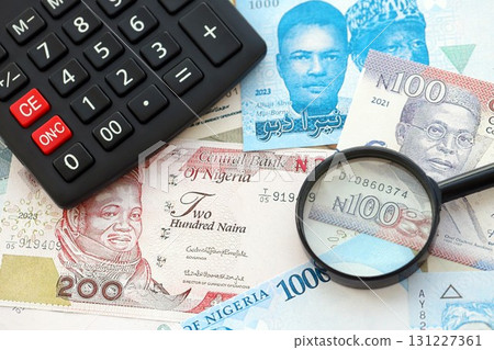 Nigerian naira currency money bills and calculator with magnifying glass. The concept of taxation and money count 131227361