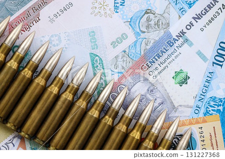 Nigerian naira currency money bills and rifle bullets. The concept of warfare and gun selling Nigerian naira currency money bills and rifle bullets. The concept of warfare and gun selling 131227368